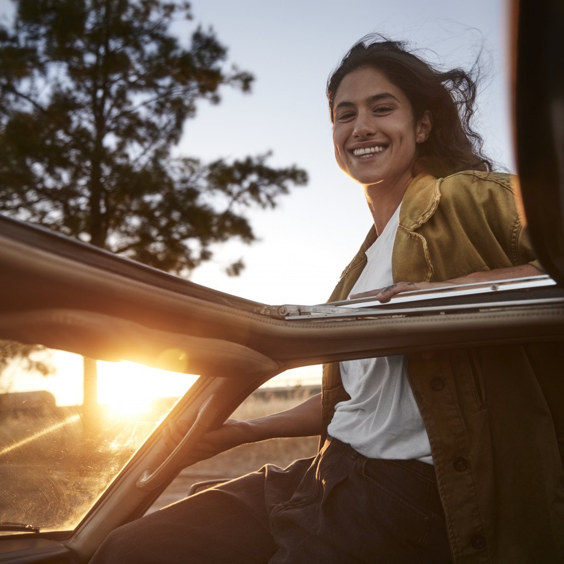 Happy young woman hanging out of the car window v2