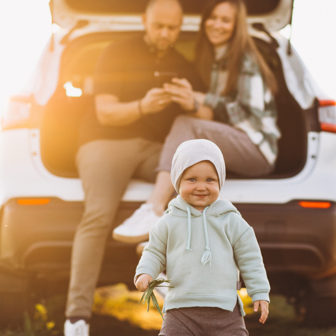 young family with kids travelling by car stopped field