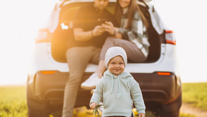 young family with kids travelling by car stopped field